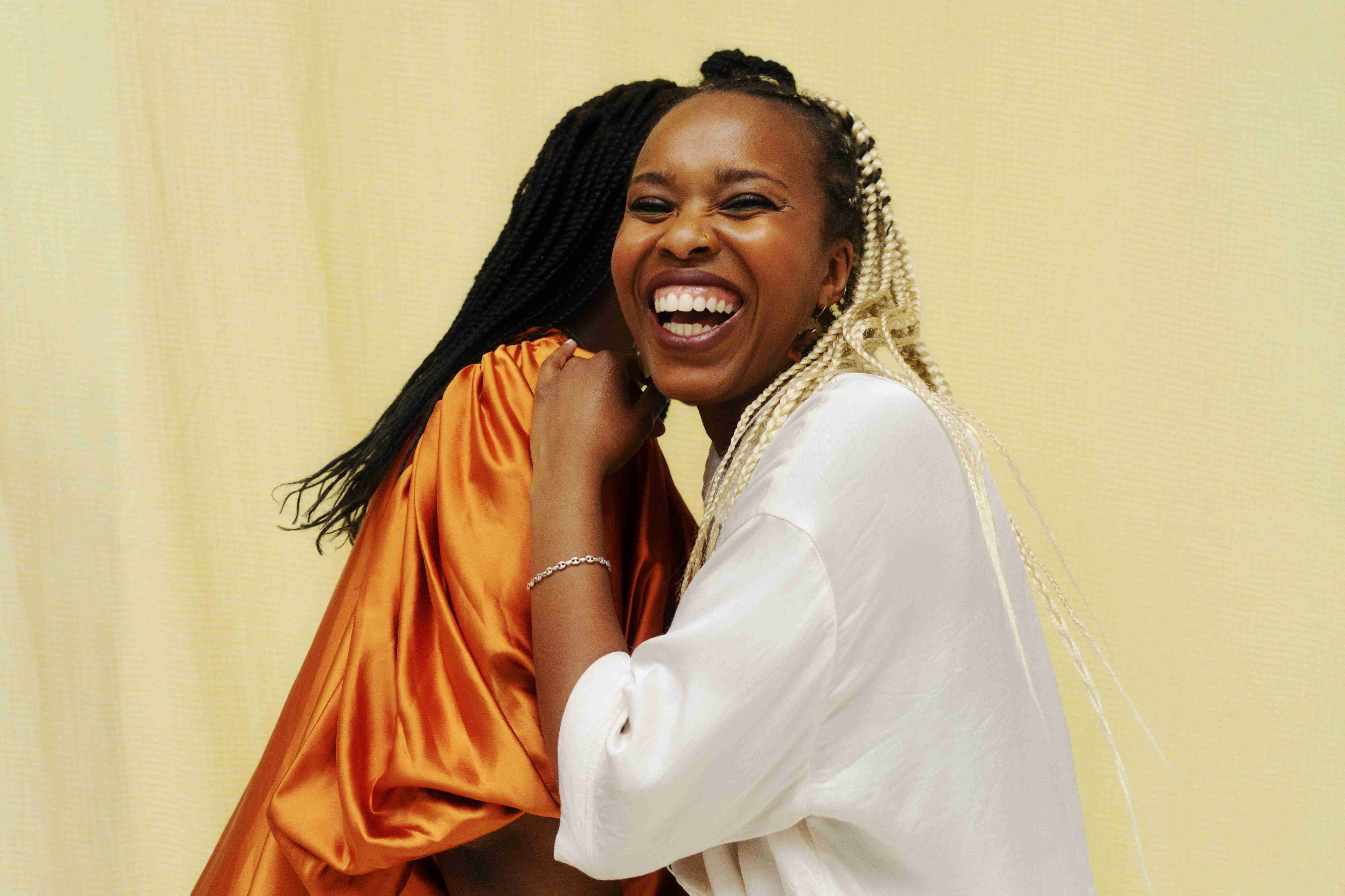 2 femmes sourient en portant des coiffures tressées