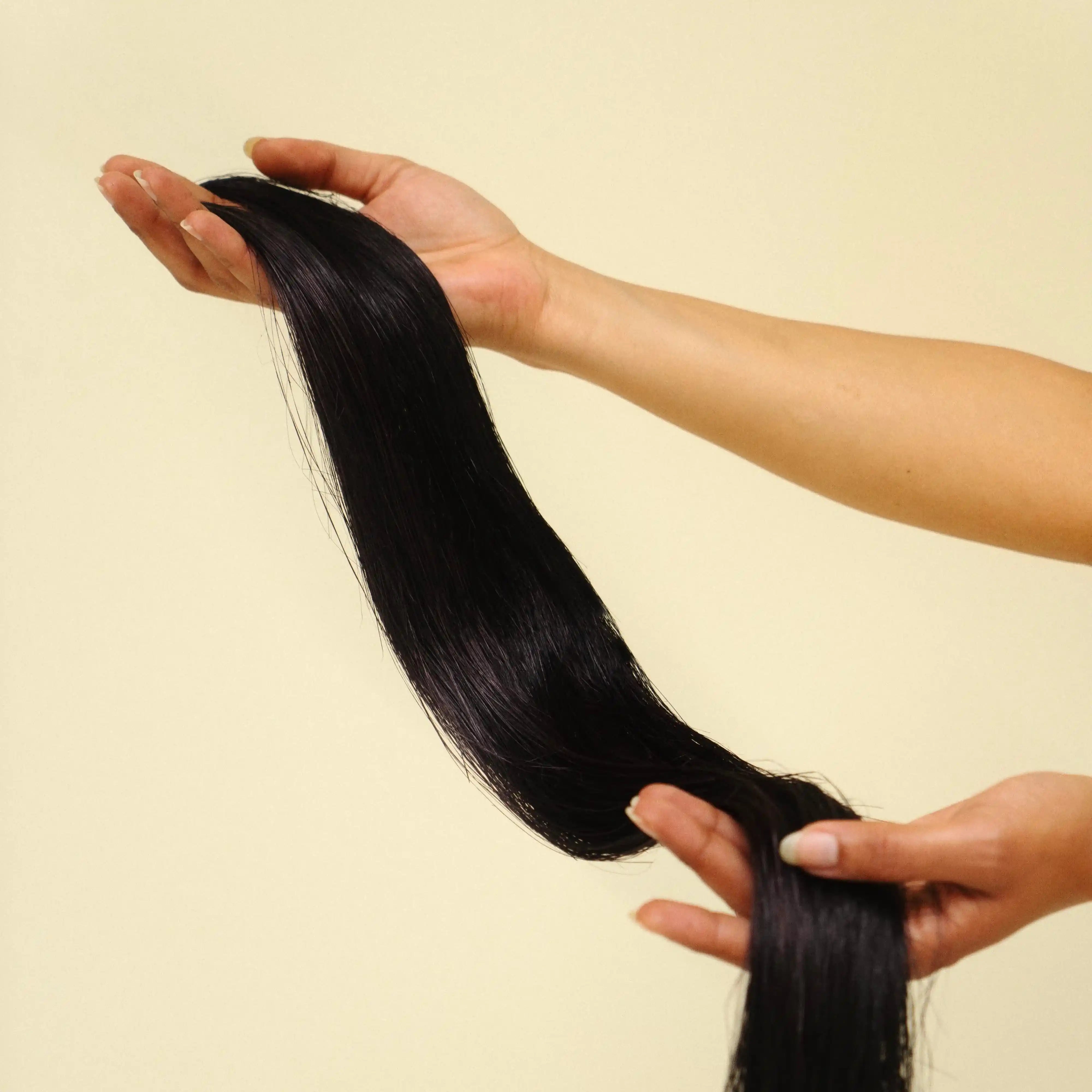 Une mèche végétale en fibre de bananier est tenue entre 2 mains