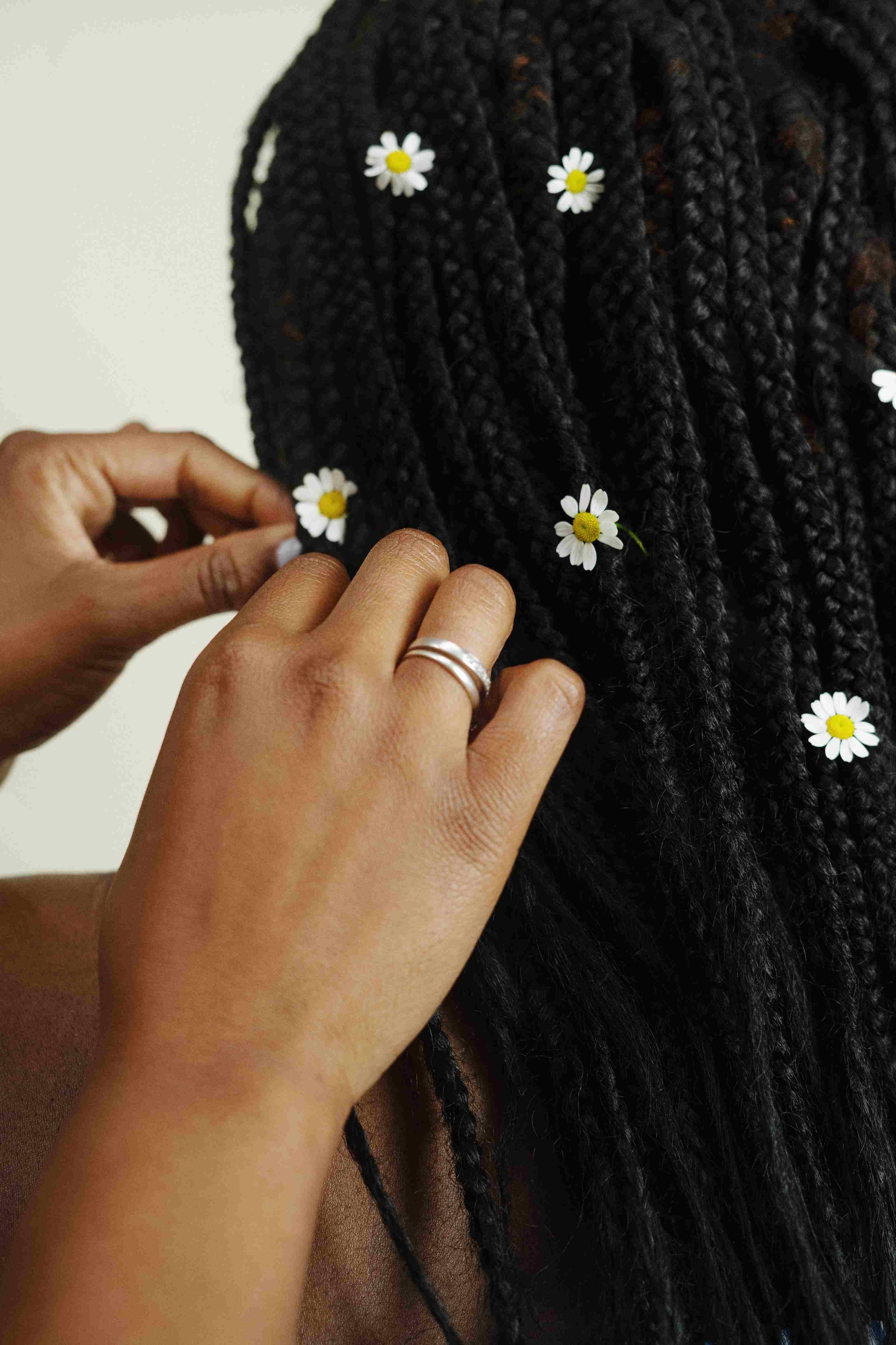 Une femme se fait mettre des fleurs dans les tresses végétales qu'elle porte