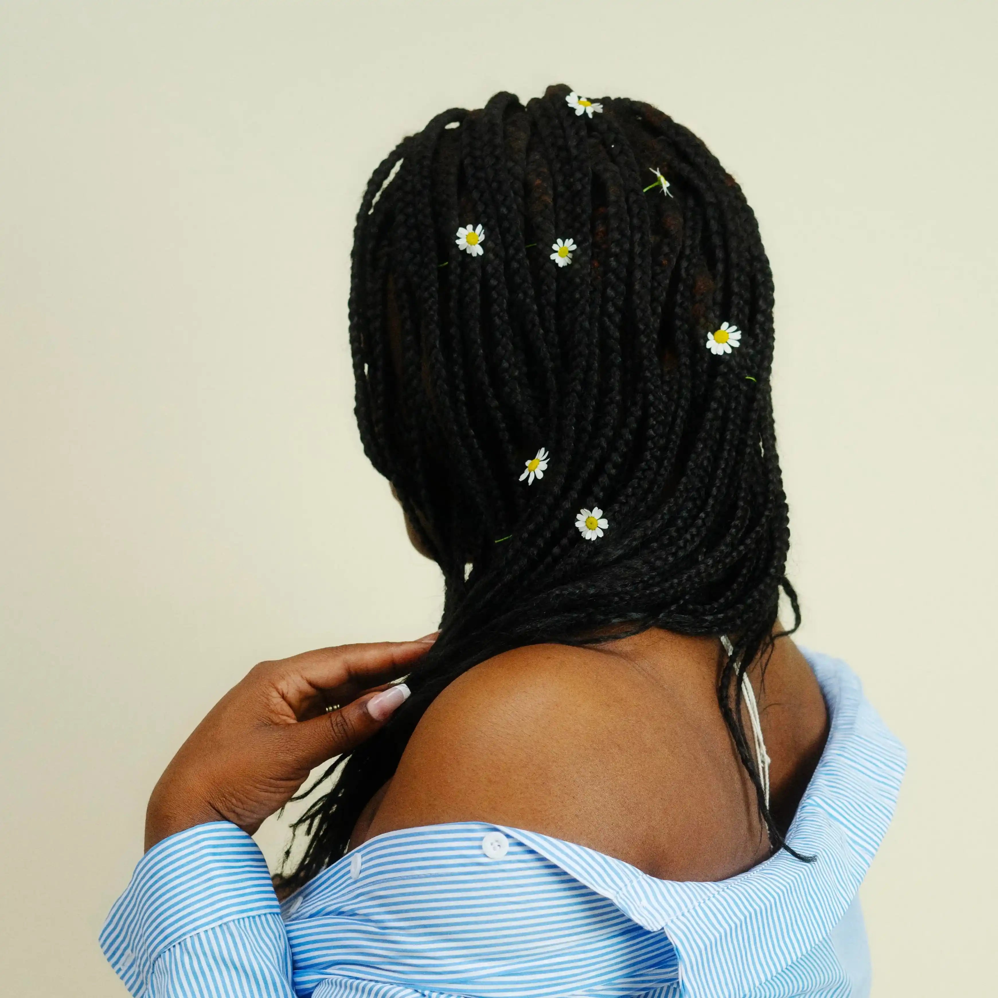 Une femme porte des mèches végétales noires tressées de dos