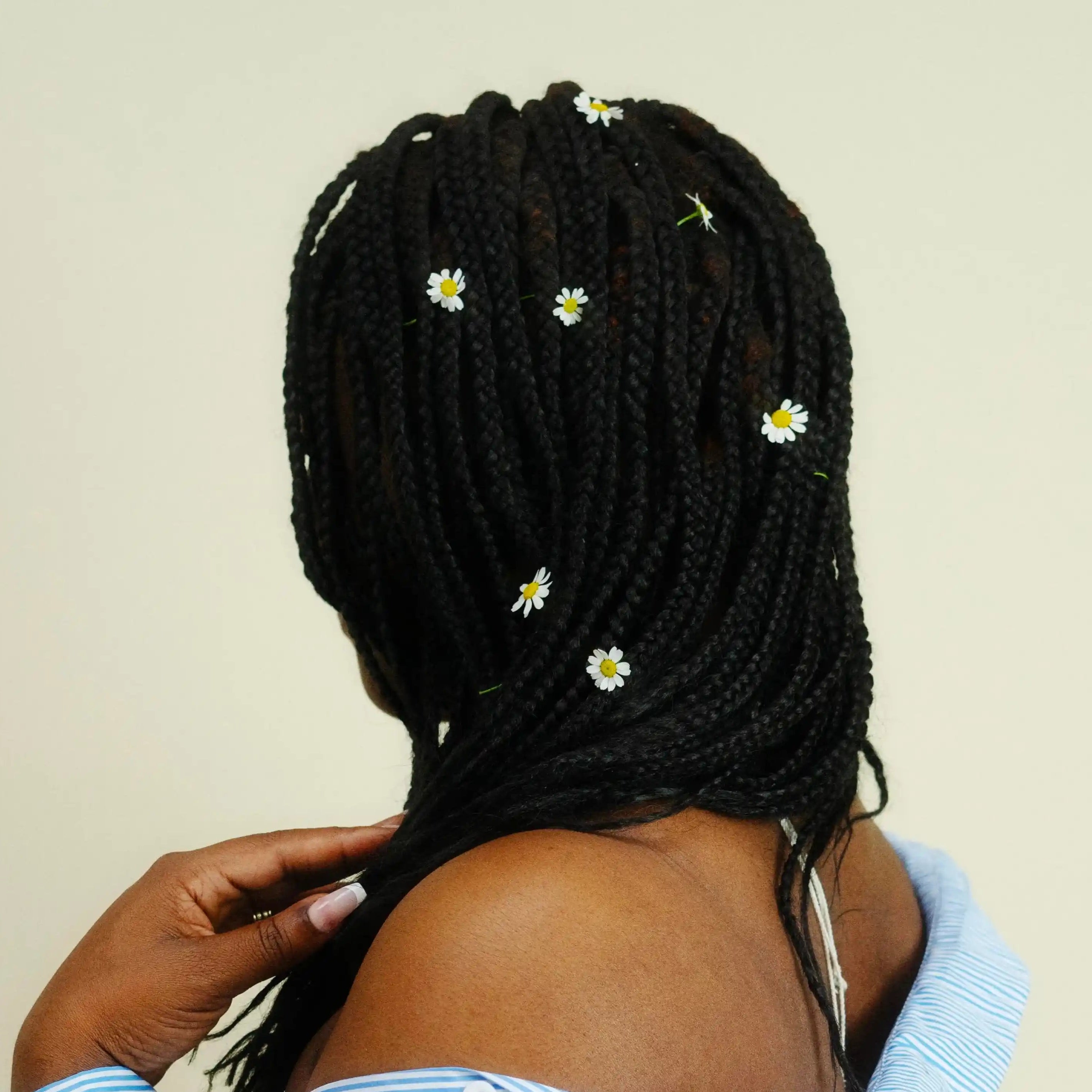 Une femme porte des mèches végétales noires tressées de dos